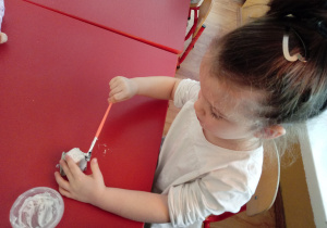 Dziewczynka maluje na biało ząb z tekturki